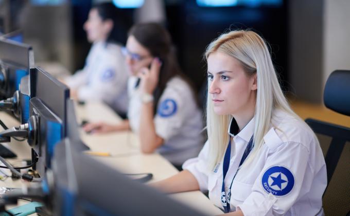 Female security operator working in a data system control room offices